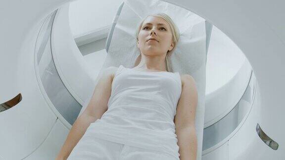 在医学实验室男性放射学家控制MRI或CT或PET扫描与女性病人进行程序高科技现代医疗设备提升相机拍摄