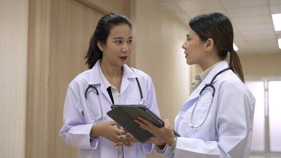 两名亚洲女医生站在医院走廊上随意交谈