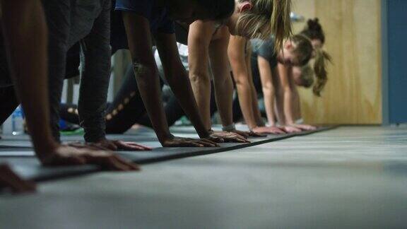 一群20多岁的女性在健身房里做俯卧撑和平板支撑