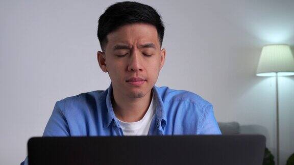 年轻的亚洲商人在家里使用笔记本电脑工作时看起来很严肃和紧张