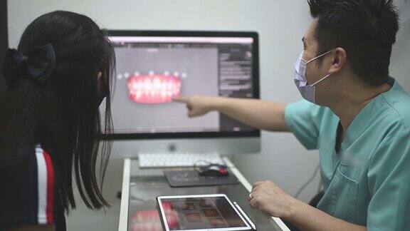 亚洲华裔男性牙医向病人解释牙齿x光片