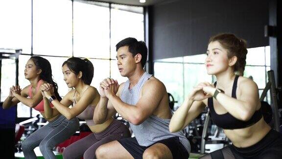 一组运动的年轻亚洲人在运动服装做下蹲和锻炼在健身房激烈的锻炼和健康的生活方式概念