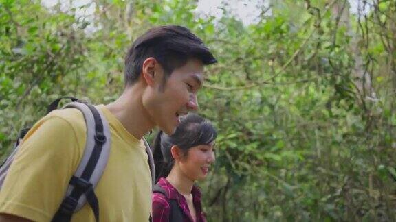 年轻的亚洲男人和女人朋友一起在森林里旅行情侣们在大自然中感受清新和放松看着窗外的风景然后带着幸福和乐趣继续散步