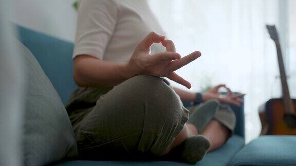 在家里客厅的沙发上女性双手握着瑜伽姿势冥想的特写镜头