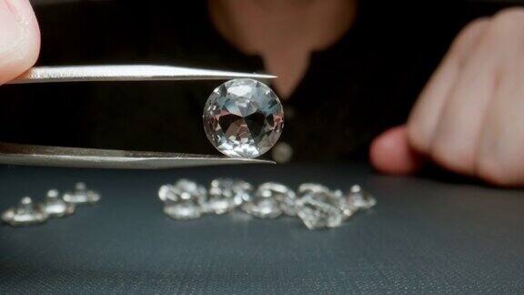 微距:珠宝商拿着一颗钻石用镊子显示它的特写