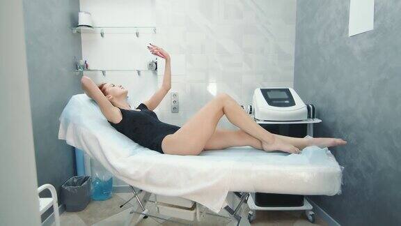 一位女士正躺在美容院的沙发上等待减肥手术女人翻看手机磁带