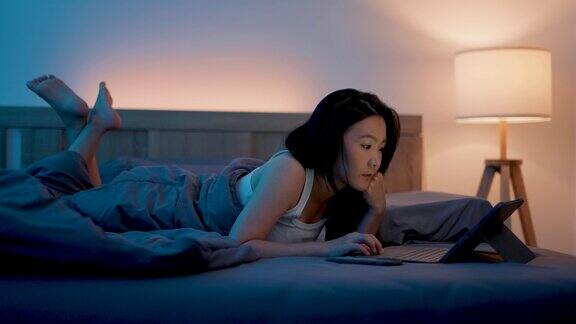 亚洲女性晚上在卧室里玩平板电脑
