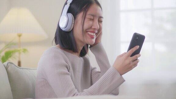 亚洲年轻女性会放松下来享受她们一起听的音乐女人度假时戴着耳机坐在沙发上在家听自己喜欢的歌