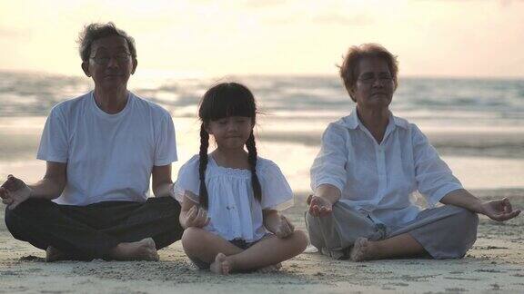 日落时在沙滩上做瑜伽的爷爷奶奶和孙女的剪影家庭生活方式人人寿保险多代人老人假期关系孩子假期退休健康护理领导理念