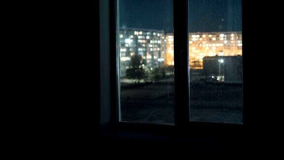 透过窗户观看在高层建筑的窗户在晚上的灯光