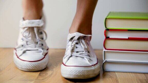 穿着白色运动鞋的学生地上有一堆书学生、教育和知识观念