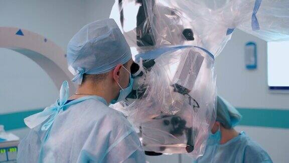 医生进行神经外科手术两位神经外科医生在手术室的显微手术中观察当代显微镜