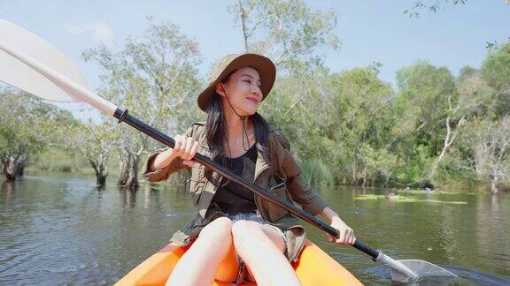 亚洲年轻迷人的女游客独自在森林湖划皮艇背包旅行者女孩旅行和皮划艇在美丽的红树林享受花时间度假旅行