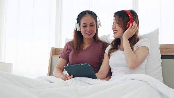 戴着无线耳机的两姐妹正在听平板电脑上的音乐