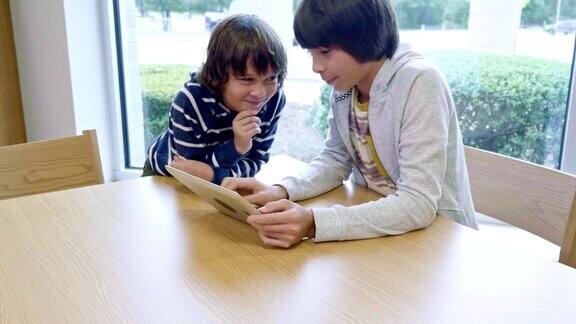两个西班牙兄弟在学校图书馆看数字平板电脑