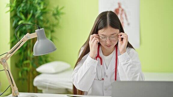 年轻的中国女医生戴着眼镜在诊所使用笔记本电脑