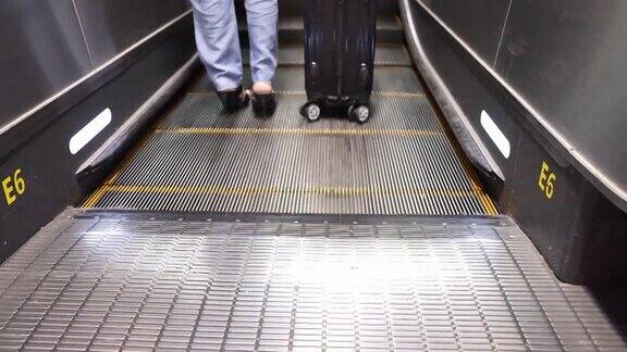 女商人的腿和行李站在自动扶梯机场的特写