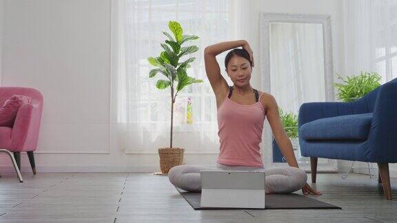 居家女性用数字平板在线学习瑜伽伸展她的肩膀和脖子
