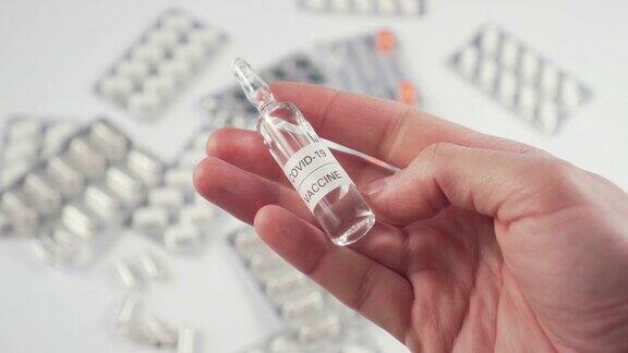 冠状病毒疫苗安瓿在手药丸和医疗胶囊的背景