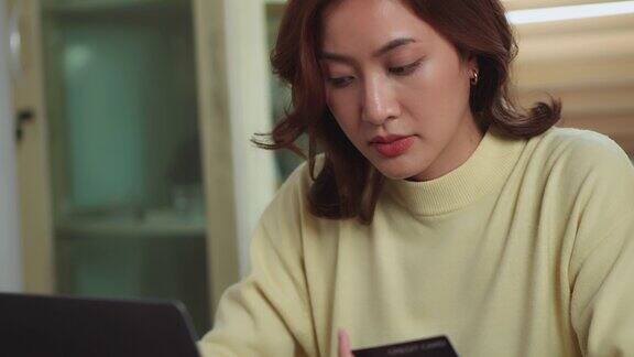 亚洲女性手持信用卡使用笔记本电脑在线支付