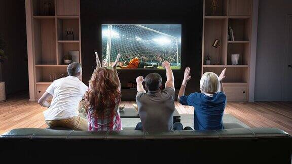一群学生正在看电视上的足球时刻庆祝进球