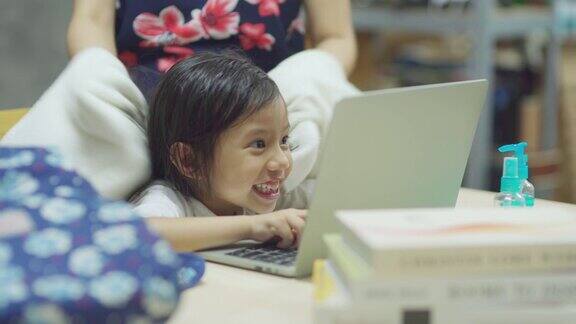 近距离的亚洲女儿玩笔记本电脑准备第一天的学校