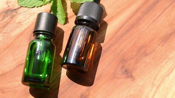 棕色和绿色的精油瓶子天然护肤化妆品木桌上放着一瓶和新鲜的薄荷注重健康和美丽