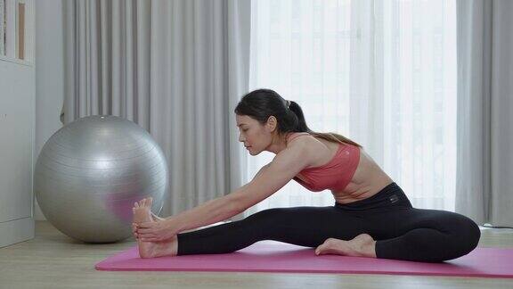 亚洲妇女的柔韧性训练同时做瑜伽练习在她的家
