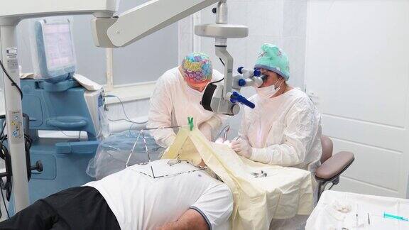 两位女外科医生用显微镜和医疗器械进行眼科手术