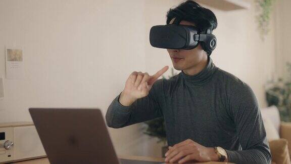 亚洲男人在家带着VR眼镜工作