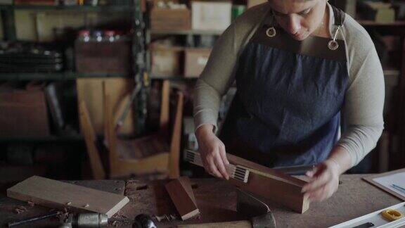 一名妇女在木工店的长凳上测量木材