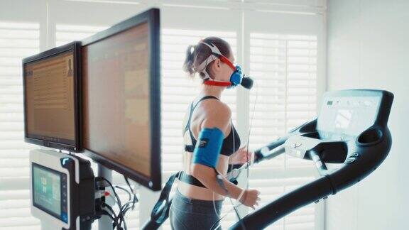 运动员在运动中心进行健康检查在运动机上跑步监测血压、呼吸和心率显示医学耐力和性能测试结果的计算机