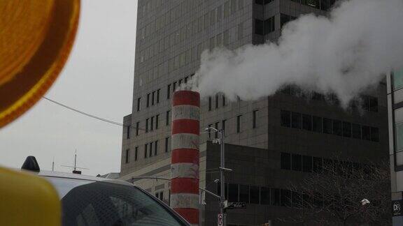 蒸汽从施工管道中喷出前景是警示灯背景是城市办公大楼
