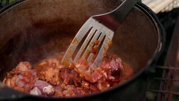 在大铁锅里准备菜用红洋葱和肉等组成