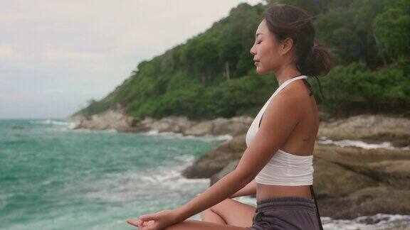 亚洲妇女在岩石上练习冥想