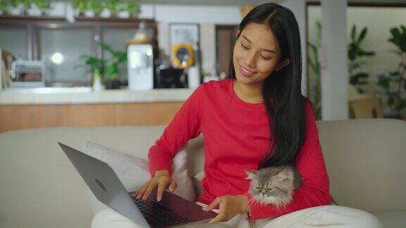 年轻的亚洲女人和她的猫坐在客厅里