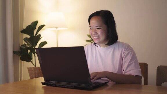 快乐的女人晚上使用笔记本电脑