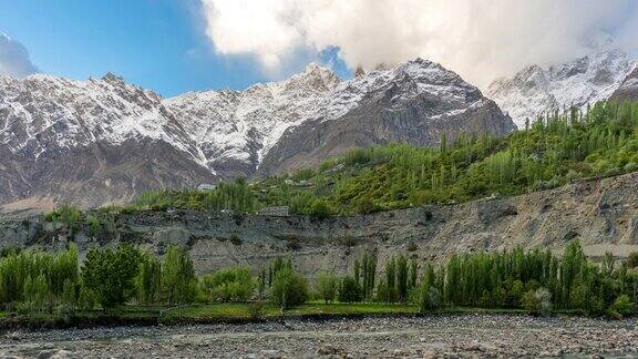 在巴基斯坦罕萨山谷的春天喀喇昆仑山脉的雪山的雄伟景色的延时移动云雾日出场景