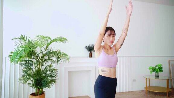 年轻的微笑迷人的运动亚洲女性练习瑜伽做Virabhadrasana1练习在勇士瑜伽姿势冥想在家室内锻炼穿着运动服实时4k视频