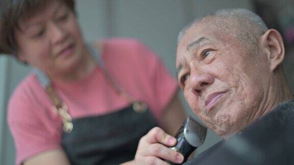 一名亚洲华人女子在白天坐在轮椅上为父亲理发