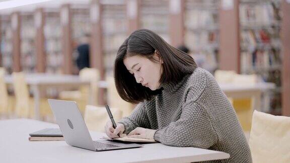 亚洲大学生在图书馆使用笔记本电脑