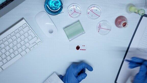 在使用显微镜载玻片时戴着防护手套的实验室助理手上的俯视图