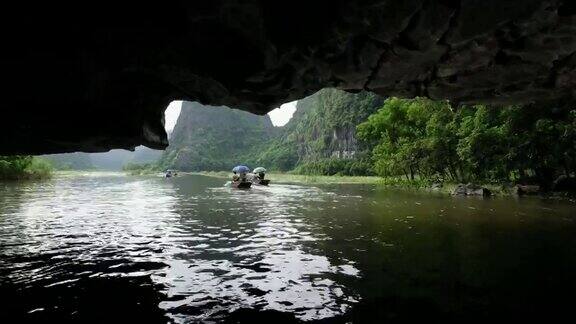 越南宁平游客们坐在传统的划艇上离开吴东河石灰岩山谷的山洞