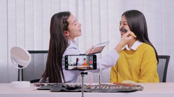 年轻的亚洲女性制作视频为自己的博客上的化妆品现在的产品和直播视频到社交网络通过互联网在家庭美容博客