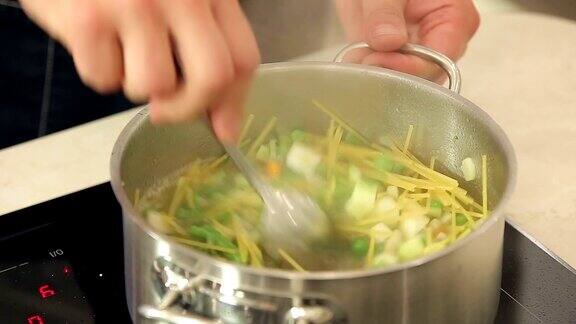 厨师正在把意大利面放进一个沸腾的蔬菜汤锅里