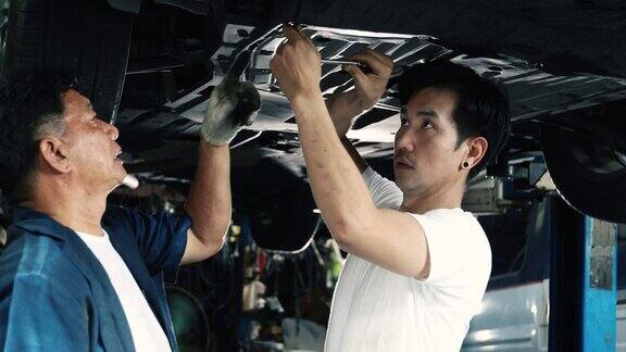 老年机械教学人员在车库维修汽车悬架
