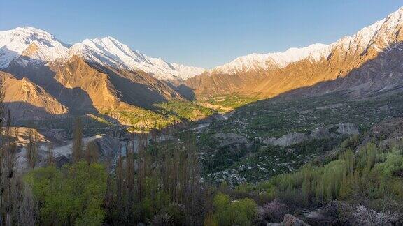 在巴基斯坦北部罕萨山谷地区的春天喀喇昆仑山脉的雪山的壮丽景色的延时移动光影日出