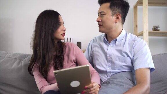 亚洲夫妇正在平板电脑上观看或阅读新闻他们对看到的一些新闻感到震惊一对夫妇对他们在网上看到的关于夫妻和生活方式的新闻感到惊讶