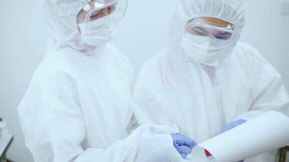 冠状病毒大流行期间两名身穿防护服的医务人员在剪贴板上讨论检测结果
