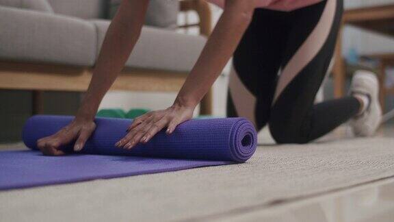 一位美女在家里做完运动后蜷缩起来保存瑜伽垫